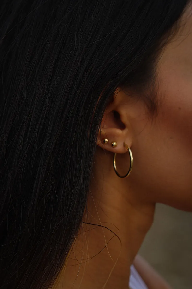 Ear with a curated stack of small studs and a thin gold hoop