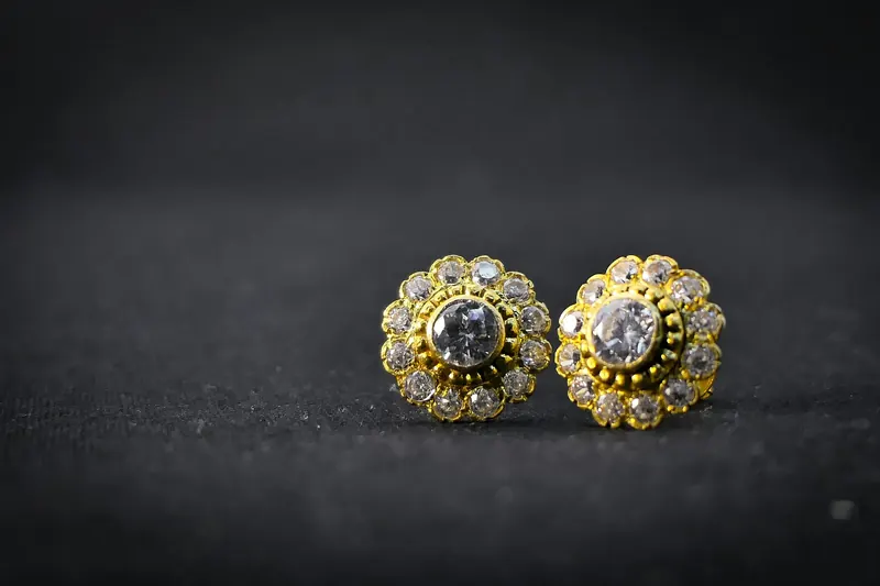 Two gold flower-shaped crystal stud earrings on a dark background, similar to 8mm earrings actual size